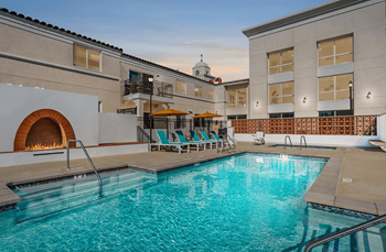 A large outdoor swimming pool with a hot tub and lounge chairs.